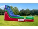 15ft dinosaur water slide rental in Austin with wet and dry functionality, featuring colorful retro striped design and landing
