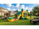 Green and yellow 2-lane fiesta bounce house with dual slides and basketball hoop rental in Austin, ideal for backyard birthday