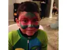 Professional face painter with red and green design available for rental in Houston—perfect for kids' parties in Conroe.