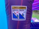 Purple Frozen bounce house rental for Irving parties with safety procedure labels on durable inflatable.