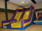 Purple and yellow inflatable rockwall and slide rental in Austin, ideal for Pflugerville birthday parties and indoor events.