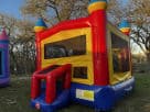 Red and yellow castle moonwalk bounce house rental in Houston backyard, 15x15 with basketball hoop, ideal for Pearland parties.