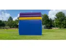 Colorful inflatable rockwall and slide rental in Austin with stacked blue, yellow, and purple sections, ideal for San Marcos