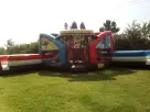 Justice League obstacle course bounce house with dual slides rental in Austin, ideal for superheroes ages 3-12.
