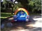 Rainbow slip n slide water rental in Austin with dual slides, ideal for kids of all ages cooling off at backyard parties in Buda.