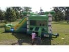 Green and yellow bounce house with dual slides at a Houston park—wet or dry rental perfect for Conroe summer parties.