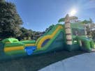 Dinosaur combo bounce house with water slide rental for Conroe parties featuring castle design and dual lanes.