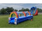 Rainbow water slide rental set up on grass in Dallas, perfect for kids cooling off at summer parties in Irving.