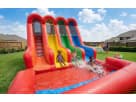 Three-lane rainbow water slide rental in Dallas with wet or dry functionality, kids racing down colorful lanes at a backyard