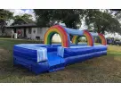 Rainbow slip n slide water rental set up on a Dallas residential lawn, perfect for kids cooling off on hot summer days